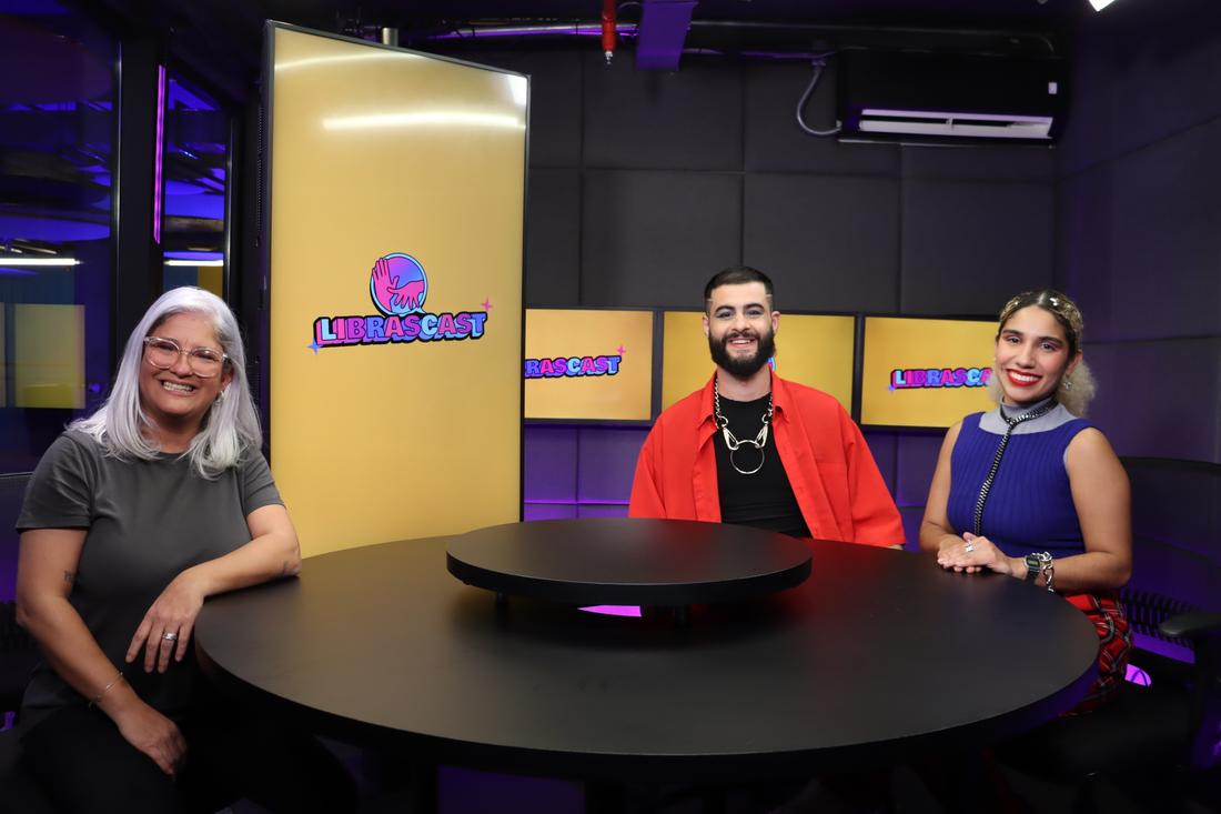 Apresentadores do LibrasCast com convidado à mesa do estúdio